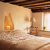 Weiß getünchte Wände in einem Schlafzimmer im Landhausstil mit Holzdecke
