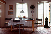 Weißes modernes Esszimmer im Landhausstil mit Ziegelsteinböden und Esstisch für das Mittagessen