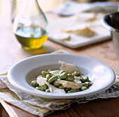 Salat aus Saubohnen und Schafskäse auf einem Tisch mit Dressing