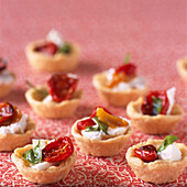 Savoury tartlets with roasted tomatoes in herb olive oil with mild goat's cheese and basil