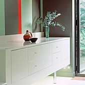 White lacquered sideboard against wall painted in bold stripes