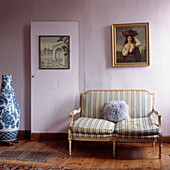Antique delicate sofa in lilac painted bedroom with wooden floors