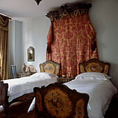 Twin bedroom with ornate antique matching single beds and headboard wall hanging