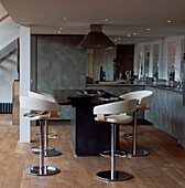 Modern kitchen area in open plan converted hall with countertop with integrated hob and bar stools
