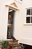 Mann vor der Haustür seines Hauses mit einer Hauskatze
