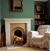Living room with green painted walls Victorian fireplace and a throw over an armchair