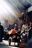 Market stalls in a narrow covered street in the medina in Fez Morocco with rays of sunlight coming through the roof