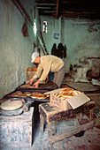 Local baker making bread in his shop in the medina Fez Morocco