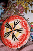 Detail of a circular embroidered cushion on a sofa