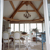 Weißes Esszimmer im Landhausstil mit Balken und Esstisch und Stühlen mit Steinboden