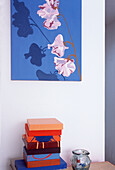 Stack of colourful paintings on canvas and one hanging on a wall in a studio space