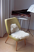 Worn green vintage chair with sheepskin rug in music room