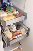 Open door in kitchen cupboard with drawers filled with grains pulses and nuts