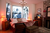 Schwarz-weißes Vintage-Kunstwerk über einem Doppelbett mit beleuchteten Lampen in einem flippigen Haus in London, England, Vereinigtes Königreich