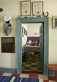 View of rustic kitchen through door from hallway with checked vinyl floor tiles