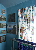 bathroom detail with naive landscape and nautical paintings and vintage boat fabric curtains 