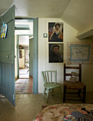 Zwei Stühle bei offener Tür im Schlafzimmer mit Gemälden und Muschelrahmen an der Wand
