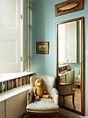 Teddybear on armchair in room corner with mirror