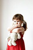 Young girl in red dress holding a teddybear