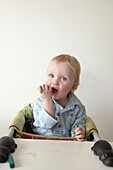 Two year old boy sits in high chair