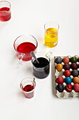 Kartontablett mit mehrfarbigen Eiern und verschiedenen Töpfen mit Farbe und Färbemitteln
