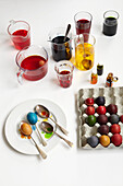 Cardboard tray of multi-coloured eggs and various pots of paint and dye
