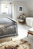 Weiß getünchtes Schlafzimmer im Dachgeschoss mit eigenem Bad mit freistehender Badewanne