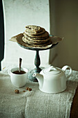 White ceramic teapot and cup with cookies on cake stand in Zermatt home, Switzerland