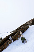 Champagnerflasche und Flöten mit Felsen im Schnee am Berghang in Zermatt, Wallis, Schweiz