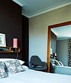 Bedroom with dark feature wall and large wall mirror and armchair