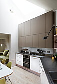 Brown fitted units in contemporary open plan kitchen of London home, England, UK