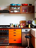 Orange retro-fitted kitchen in colourful London home, England, UK