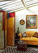 Gelbes Sofa mit Paravent in einer Wohnung in London, England, UK