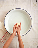 Frau wäscht Hände in einer Emailleschüssel