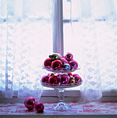 Glass baubles in a tiered cake stand in window setting