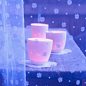 Votive candles on doilies behind snow flake net curtain