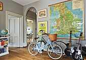 Bicycles and guitars with large wall-map of Great Britain in entrance hallway of family home, Rye, East Sussex, England, UK