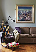 Framed artwork above sofa with rocking chair in living room of family home, Rye, East Sussex, England, UK