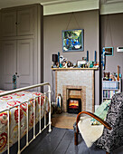 Kachelkamin mit Sessel und Trittbrett im Schlafzimmer eines Familienhauses in Rye, East Sussex, England, UK