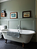 Freestanding bath in light green panelled bathroom in Rye family home, East Sussex, England, UK