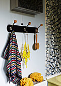 Gemustertes Handtuch und Rückenbürste hängen mit Schwämmen im Badezimmer eines Hauses in Hackney, East London, UK