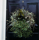 Christmas wreath of mistletoe and lichen on black front door