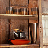 Close up of oriental style glazed tableware and decorative glassware on display in wooden cabinet