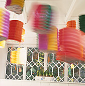 Colourful Chinese lanterns hanging from ceiling of white room