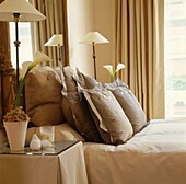 Geknöpfte Kissen auf einem Doppelbett mit passenden Lampen und Orchideen