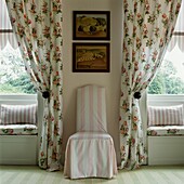 Floral curtains and window seats with upholstered striped pink and white chair