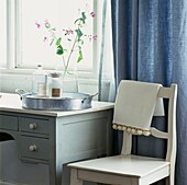 Toilettenartikel und Silbertablett auf Schminktisch am Fenster mit Vorhang und Stuhl
