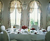 Floral patterned curtains at French doors behind table set with summer fruits