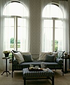 Co-ordinated daybed and ottoman with tea tray in front of arched windows with netting