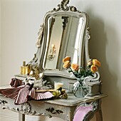 Vase of roses and clothing with mask on dressing table with mirror 